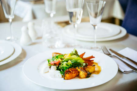 Different grilled and caramelized vegetables with fresh green salad on white plate