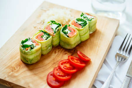 Cucumber and smoked salmon roll-ups on wooden boardの写真素材