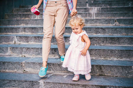 Mother and daughter walk down the stairs during a walk outdoorsの写真素材