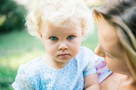 Young beautiful mother with her toddler blonde daughter during a walk outdoorsの写真素材