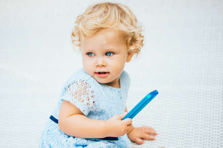 Portrait of cute blonde baby girl with smartphoneの写真素材