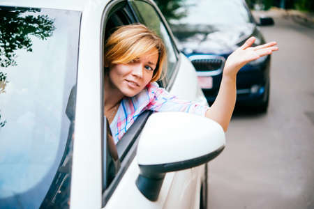 Young woman gets annoyed while driving the car in traffic jamの写真素材
