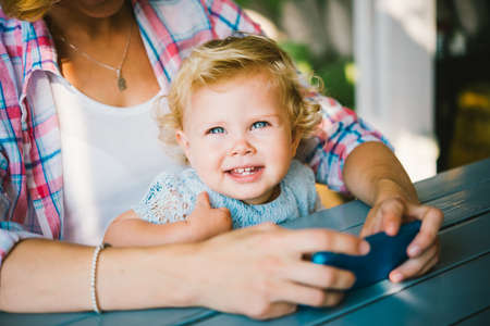 Young beautiful mother with her toddler blonde daughter during a walk outdoorsの写真素材