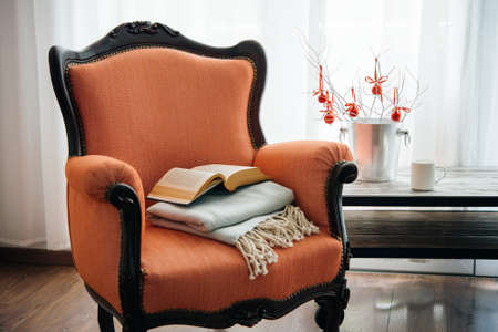 Book, cup and warm plaid on cozy retro armchair. Christmas or new year decoration conceptの写真素材