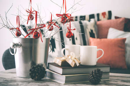 Christmas or new year decoration on modern wooden coffee table. Cozy sofa with pillows on a background. Living room interior and holiday home decor concept. Toned pictureの写真素材