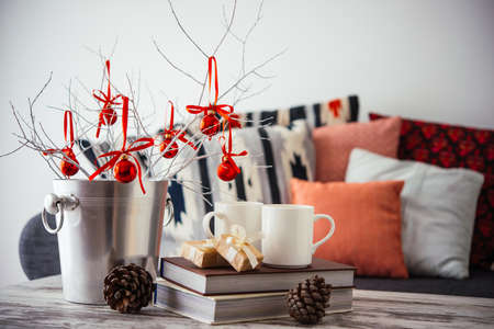 Christmas or new year decoration on modern wooden coffee table. Cozy sofa with pillows on a background. Living room interior and holiday home decor conceptの写真素材