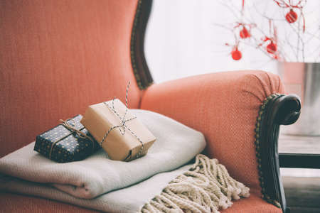 Gifts and warm plaid on cozy retro armchair. Christmas or new year decoration concept. Toned pictureの写真素材