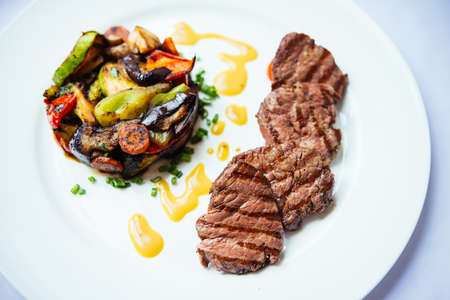 Beef medallions with grilled vegetables on white plate