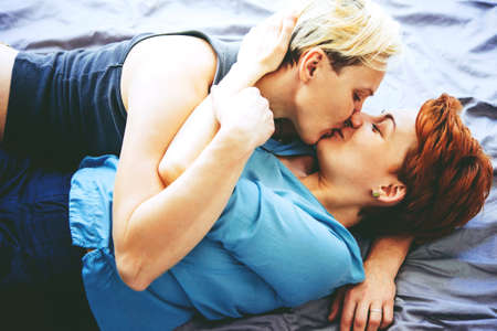 Beautiful lesbian couple cuddling in bed. Toned pictureの写真素材