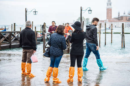 VENICE, ITALY - OCTOBER 14, 2015: Tourists wearing rain boots walk around San Marco square in rainy weather in Venice, Italy.のeditorial素材
