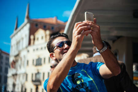 VENICE, ITALY - OCTOBER 12, 2015: Tourist takes pictures on his mobile phone during a trip on vaporetto in Venice, Italy.のeditorial素材