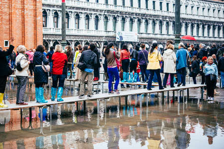 VENICE, ITALY - OCTOBER 14, 2015: Tourists wearing rain boots walk around San Marco square in rainy weather in Venice, Italy.のeditorial素材