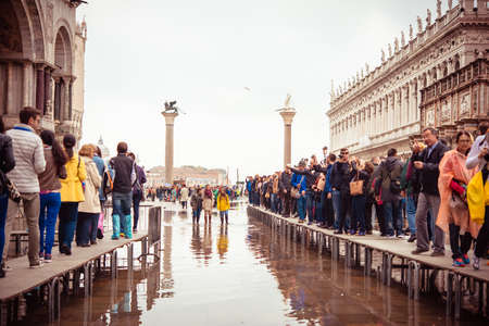 VENICE, ITALY - OCTOBER 14, 2015: Tourists wearing rain boots walk around San Marco square in rainy weather in Venice, Italy.のeditorial素材