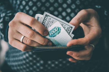Hands holding russian rouble and us dollar bills and small money pouch. Toned pictureの写真素材