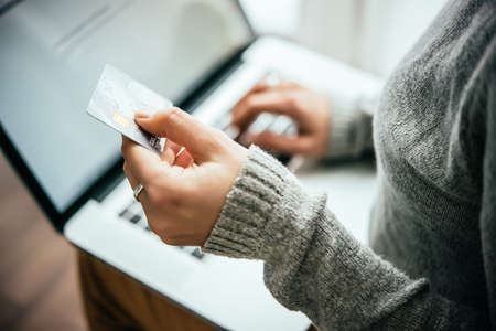 Hands holding plastic credit card and using laptop. Online shopping concept