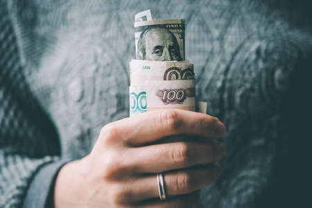 Hands holding rolled russian rouble and us dollar bills. Toned pictureの写真素材