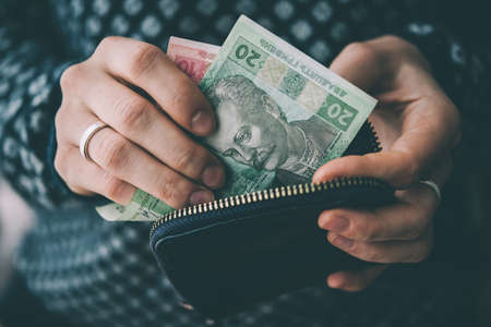 Hands holding ukrainian hryvnia bills and small money pouch. Toned pictureの写真素材