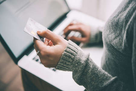 Hands holding plastic credit card and using laptop. Online shopping concept. Toned pictureの写真素材