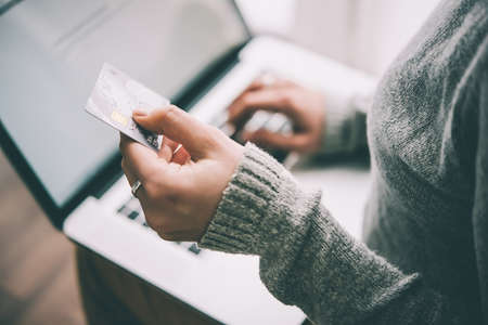 Hands holding plastic credit card and using laptop. Online shopping concept. Toned picture