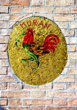 The mosaic of rooster - the symbol of Murano island is seen on the wall at Murano island, Venice, Italyのeditorial素材