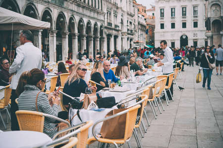 VENICE, ITALY - OCTOBER 12, 2015: Tourists are sitting in one of the cafes at San Marco square in Venice, Italy. Toned pictureのeditorial素材