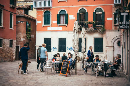 VENICE, ITALY - OCTOBER 11: People are sitting at the outside terrace of a small cafe in Venice, Italyのeditorial素材
