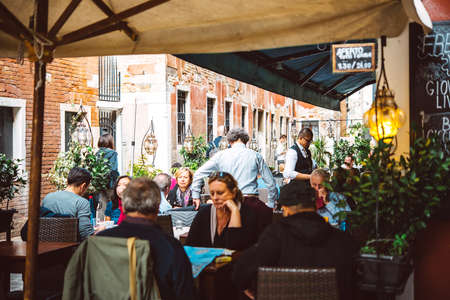 VENICE, ITALY - OCTOBER 11: People are sitting at the outside terrace of a small cafe in Venice, Italyのeditorial素材