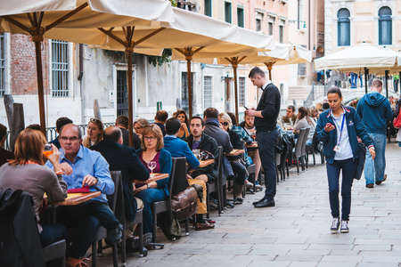 VENICE, ITALY - OCTOBER 11: People are sitting at the outside terrace of a small cafe in Venice, Italyのeditorial素材