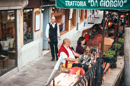 VENICE, ITALY - OCTOBER 11: People are sitting at the outside terrace of a small cafe in Venice, Italyのeditorial素材