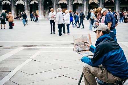 VENICE, ITALY - OCTOBER 12, 2015: A painter is drawing at San Marco square in Venice, Italyのeditorial素材