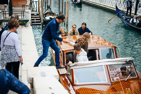 VENICE, ITALY - OCTOBER 12, 2015: Tourists are boarding the water taxi on one of the canals of Venice, Italyのeditorial素材