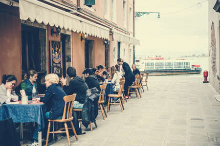 VENICE, ITALY - OCTOBER 11: People are sitting at the outside terrace of a small cafe in Venice, Italy. Toned pictureのeditorial素材
