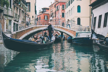 VENICE, ITALY - OCTOBER 11, 2015: Tourists are taking a gondola ride on the canals of Venice, Italy. Toned pictureのeditorial素材
