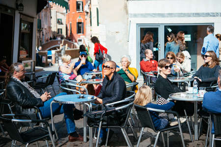 VENICE, ITALY - OCTOBER 11: People are sitting at the outside terrace of a small cafe in Venice, Italyのeditorial素材