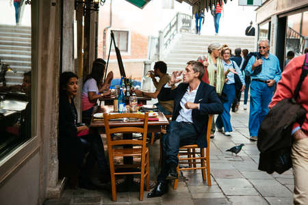 VENICE, ITALY - OCTOBER 11: People are sitting at the outside terrace of a small cafe in Venice, Italyのeditorial素材