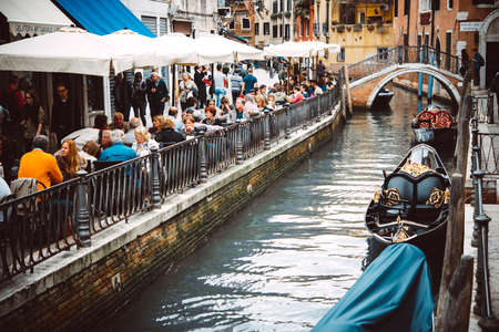 VENICE, ITALY - OCTOBER 11, 2015: People are sitting at the outside terrace of a small cafe located on one of the canals of Venice, Italy. Toned pictureのeditorial素材