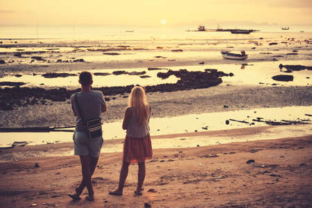 A young couple is watching a sunset at one of the beaches at Koh Samui, Thailand. Toned pictureの写真素材