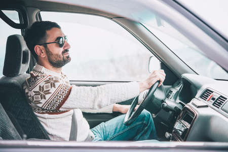 Young man drives a car in mountains. Travel and adventure concept. Toned pictureの写真素材