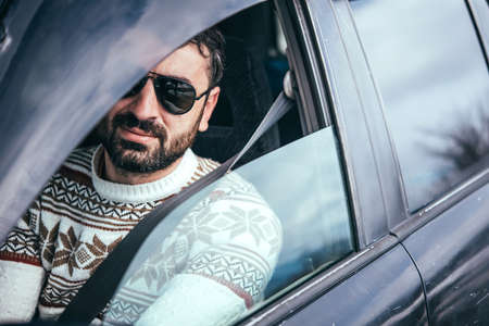 Young man drives a car in mountains. Travel and adventure concept. Toned pictureの写真素材