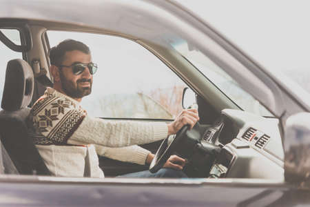 Young man drives a car in mountains. Travel and adventure concept. Toned pictureの写真素材