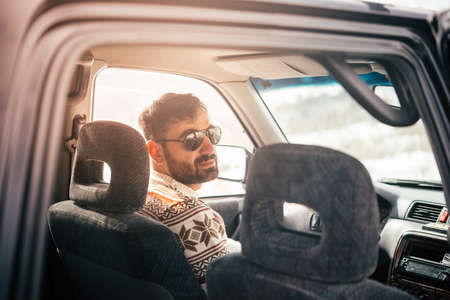 Young man drives a car in mountains. Travel and adventure concept. Toned pictureの写真素材
