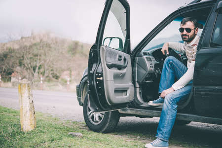 Young man driving the car in the mountains is relaxing at a roadsideの写真素材