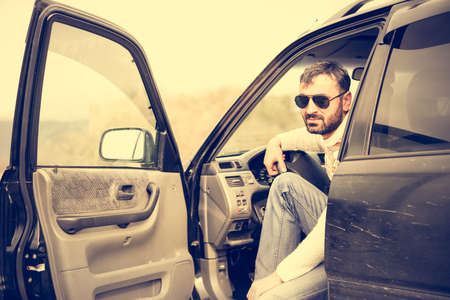 Young man driving the car in the mountains is relaxing at a roadsideの写真素材