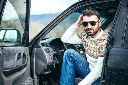 Young man driving the car in the mountains is relaxing at a roadsideの写真素材
