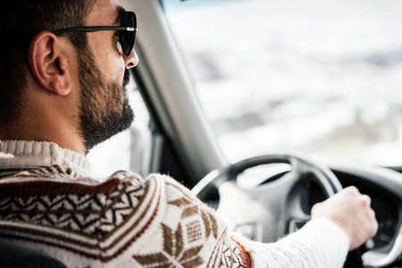 Young man drives a car in mountains. Travel and adventure concept. Selective focusの写真素材