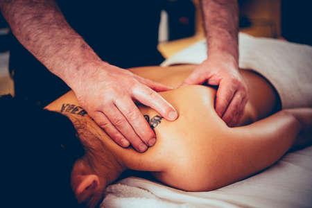 Woman enjoying relaxing back massage in cosmetology spa centre. Beauty treatment, body care, skin care, wellness, wellbeing concept. Toned pictureの写真素材