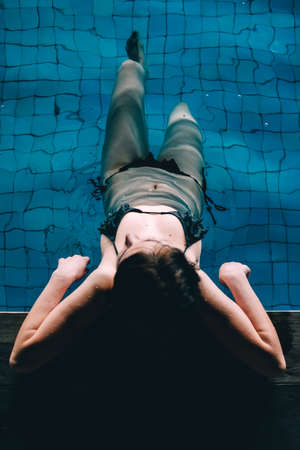 A young beautiful woman swims in a pool. Freedom concept. Calmness and relax, woman happiness.の写真素材