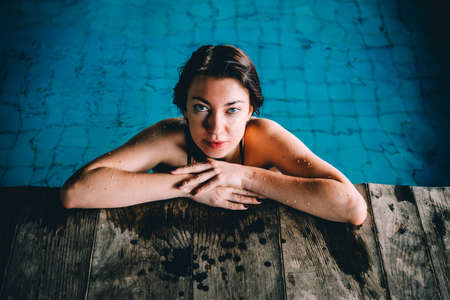 A young beautiful woman relaxes in the swimming pool. Wellness concept. Spa and relax, woman happiness.の写真素材