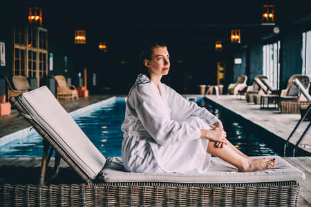 Young beautiful woman is relaxing in a bathrobe after swimming in the pool. Wellness concept. Spa and relax, woman happiness.の写真素材