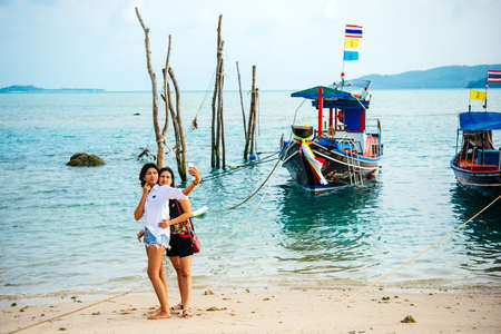 KOH SAMUI, THAILAND - MARCH 18, 2016: Tourists make selfies in front of fishing boats at Koh Samui, Thailand.のeditorial素材
